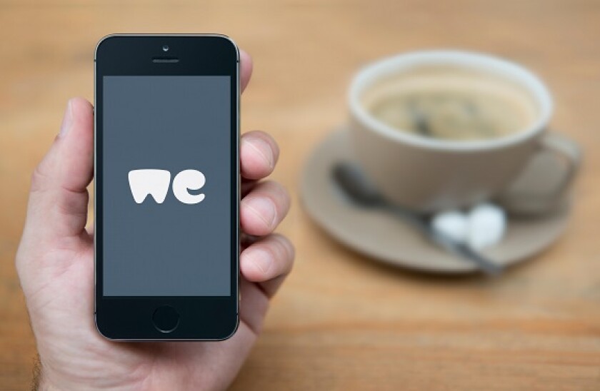 A man looks at his iPhone which displays the WeTransfer logo (Editorial use only).