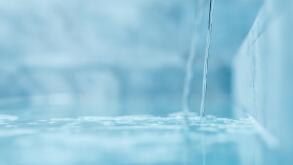 a trickle of crystal clear water is poured into the pool. Selective focus very blurred macro shot with shallow DOF