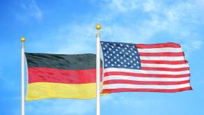 Germany and United States two flags on flagpoles and blue cloudy sky