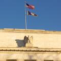 United States Federal Reserve headquarters in Washington DC, USA. Eccles Building with US National and Fed flags under clear sky in early morning.