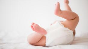 Baby girl (2-5 months) lying on bed