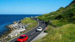 The eastern coast of Northern Ireland and Antrim Coast Road A2, a.k.a Causeway Coastal Route with cars. One of the most scenic coastal roads in Europe