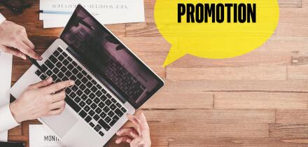 BUSINESS TEAM WORKING IN OFFICE WITH PROMOTION SPEECH BUBBLE ON DESK