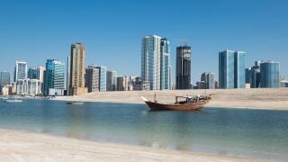 Traditional boat with modern skyline, Emirate of Sharjah, UAE.