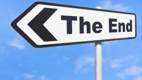 The End direction sign pointing to the left against blue sky.