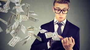 Sad worried business man looking at his wallet with money dollar banknotes flying out away