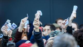 People holding up bank notes to bid at an auction, London, England, UK
