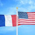 France and United States two flags on flagpoles and blue cloudy sky