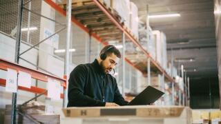 Male manual worker reading document at logistics warehouse