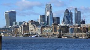The London City skyline contrasts with warehouses and moored sailing barges on the waterfront in Wapping. Viewed from Bermondsey. UK