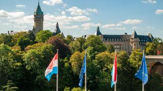 Musee de la Banque (Bank Museum, left) and State Bank and Savings Fund buildings with Luxembourg and EU flags in the foreground, Luxembourg City.