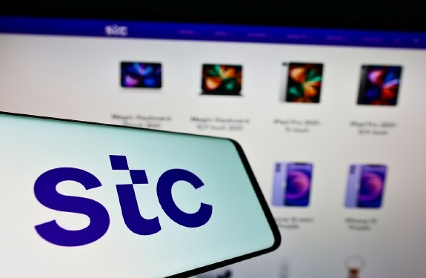 Mobile phone with logo of Arabian carrier Saudi Telecom Company (STC) on screen in front of company website. Focus on center of phone display.