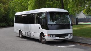 A small white tour coach, bus or mini-van used to transport passengers and tourists. Typically used for small group tours of around 21 passengers.