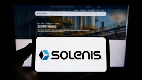 Person holding mobile phone with logo of US chemicals company Solenis International LP on screen in front of web page. Focus on phone display.