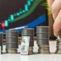 Hand Stacking Oil Barrel on Coins with Cash and Trading Chart