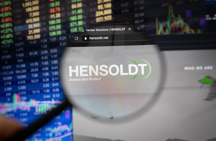 Hensoldt company logo on a website with blurry stock market developments in the background, seen on a computer screen through a magnifying glass