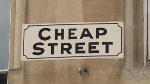Painted road sign reading Cheap Street on a stone building in the historical City of Bath, Somerset, UK