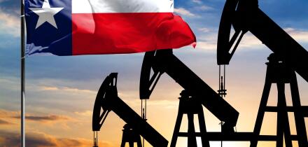 Oil rigs against the backdrop of the colorful sky and a flagpole with the flag State of Texas. The concept of oil production, minerals, development of