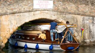 Small yacht carefully navigating the low bridge at Potter Heigham, on the Norfolk Broads, England UK