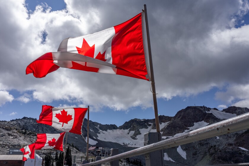 Breathtaking shot of Canadian flags flying at top of Whistler Mountain, BC, Canada