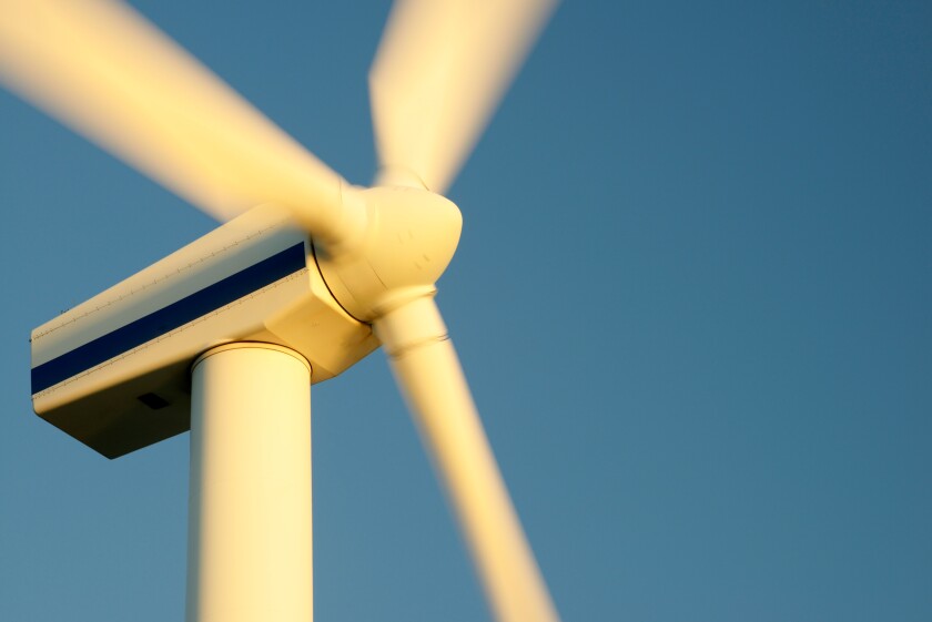 Wind turbine rotors with blue sky generating electricity on wind farm at Workington, Cumbria, England, UK. Warm evening light