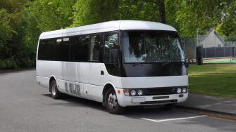 A small white tour coach, bus or mini-van used to transport passengers and tourists. Typically used for small group tours of around 21 passengers.