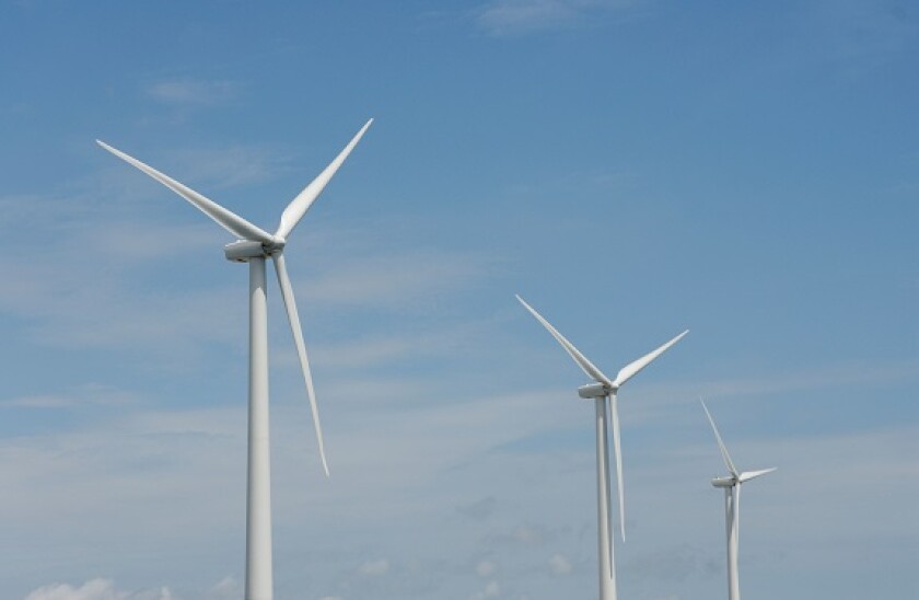 Three wind turbines, close-up of blades, against blue sky. Wind power "wind farm" turbines alternative energy, renwable energy.