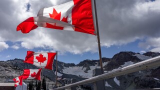 Breathtaking shot of Canadian flags flying at top of Whistler Mountain, BC, Canada