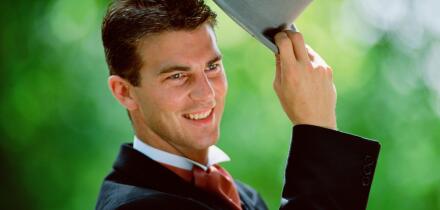 Lifestyle. Wedding. Man outdoors raising his top hat.