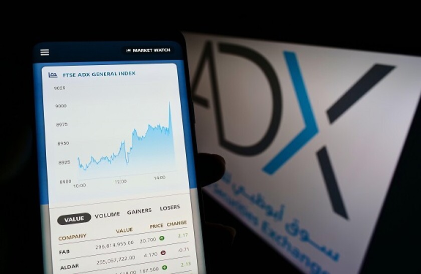 Person holding smartphone with webpage of company Abu Dhabi Securities Exchange (ADX) on screen with logo. Focus on center of phone display.