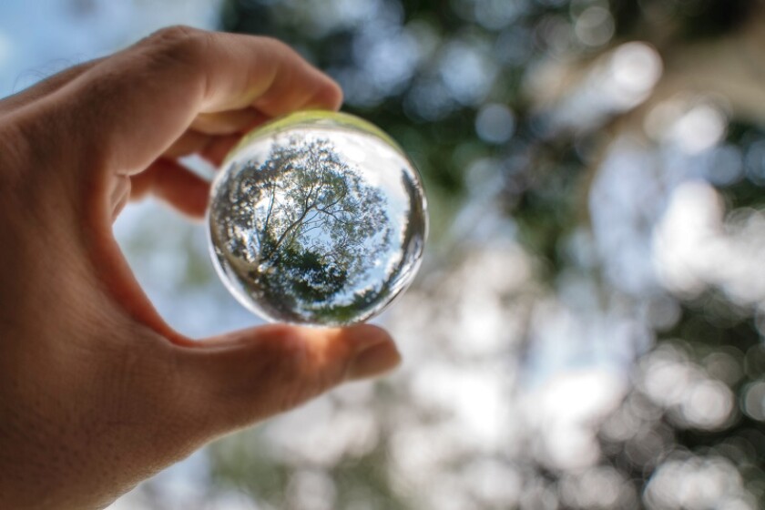 Reflection of blue sky, white clouds and trees in a glass ball i