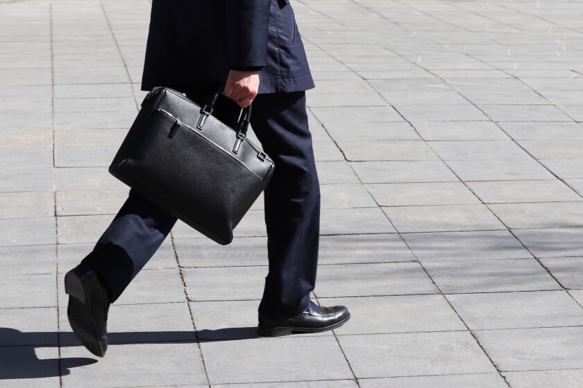 Man with briefcase walking on the street, person in a business suit rushing to a meeting. Concept of businessman, official, politician, career