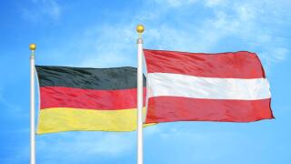 Germany and Austria two flags on flagpoles and blue cloudy sky