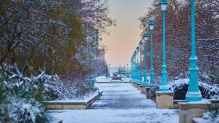 Winter cityscape of Paris with a snowy walkway lined with street lamps and trees, captured at sunrise