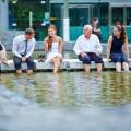 Happy business people talking during break in summer with their feet in water