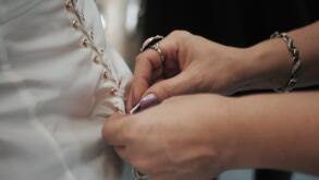 Stylist helps to tighten the corset of a historical dress on woman. 18th century look. Hands close-up.