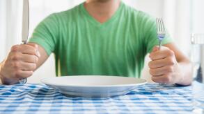 Mixed race man holding fork and knife at table