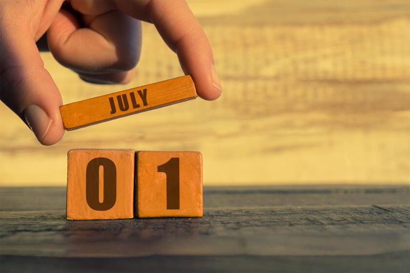 july 1st. Day 1 of month, calendar on a wooden cube. a woman's hand puts the name of the month on the number of the month on a wooden background summe