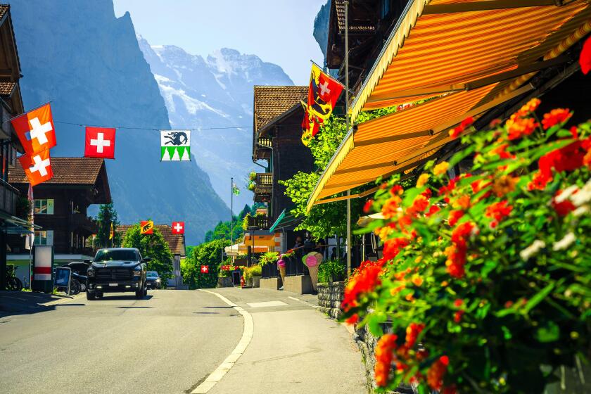 Picturesque cozy alpine village with shops and rustic wooden houses. Cute mountain village with flowery street and high mountains in background, Laute