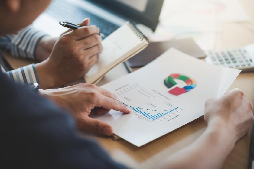 Businessman hand holding report document in office meeting room with business discussion and brainstorm atmosphere in blurry background.