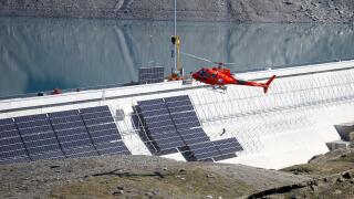 A helicopter flies past the construction site of a large-scale photovoltaic system of Swiss energy provider Axpo at some 2500 metres above sea level on the dam of Lake Muttsee, Switzerland August 19, 2021. Picture taken August 19, 2021.   REUTERS/Arnd Wie