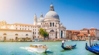 Traditional Gondola and boat on Canal Grande with historic Basilica di Santa Maria della Salute in the background, Venice, Italy