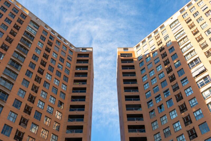 Low angle view of two symmetrical buildings of straight lines with a space between them with a blue sky above them. Architecture concept