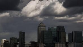 Dark storm clouds over Canary Wharf business park buildings in London
