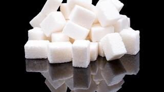 Cubes of white sugar from sugar beet with a real reflection on a black glossy background