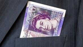 Banknotes of British pounds sticking out out of the businessman suit pocket. Money in the pocket of business suit