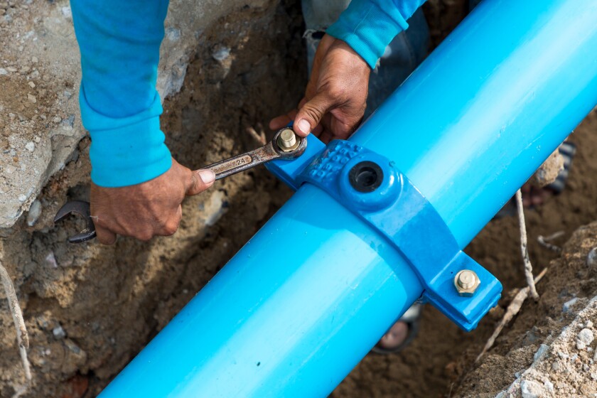 Man using a large wrench on water pipes. Construction site with 