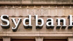 Sign of the danish sydbank in white letters on a brownish facade in Svendborg, Denmark, July 10, 2019