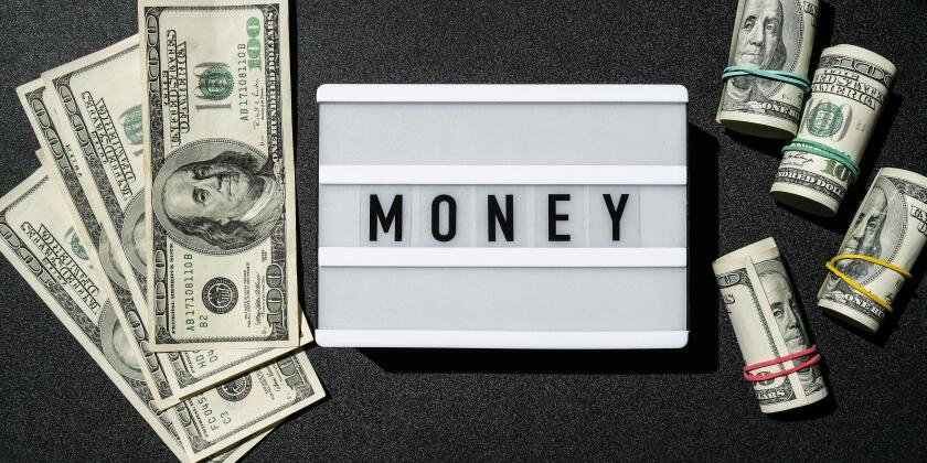 Lightbox board with the word MONEY in black letters around Us dollar banknotes. Finance background. Business, financial success and making money