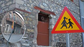 Traffic sign, warning people to be careful of people crossing the street as seen in a traffic mirror at the village of Kanalia, Karditsa, Greece.